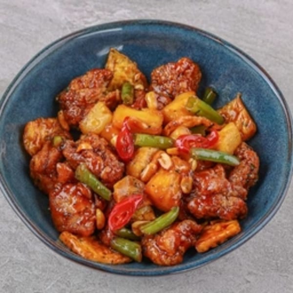 Okinawa's sweet and sour chicken with pineapple, peppers, and green beans in a blue bowl.